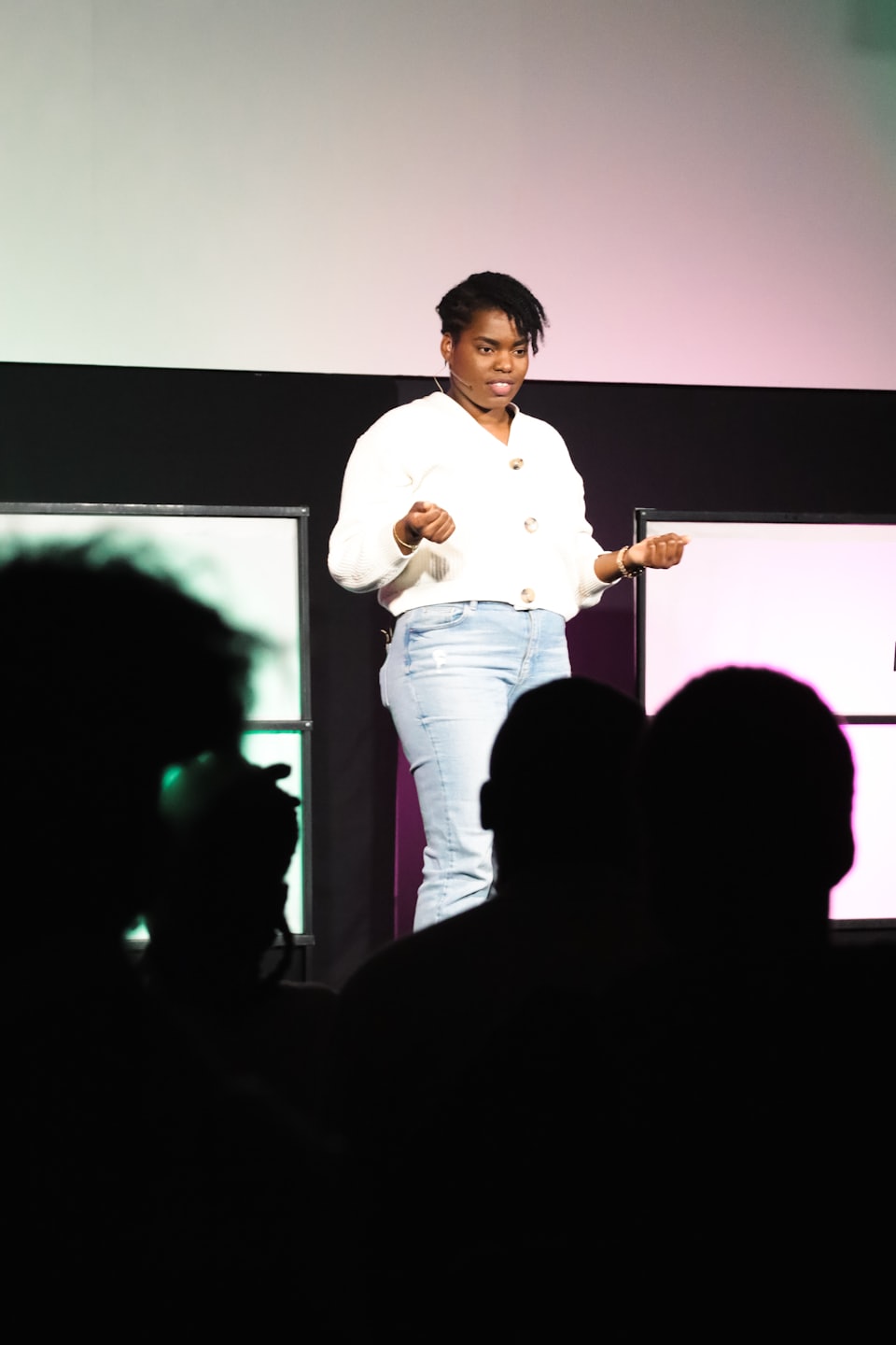 Speaker gestures while addressing audience from a stage.